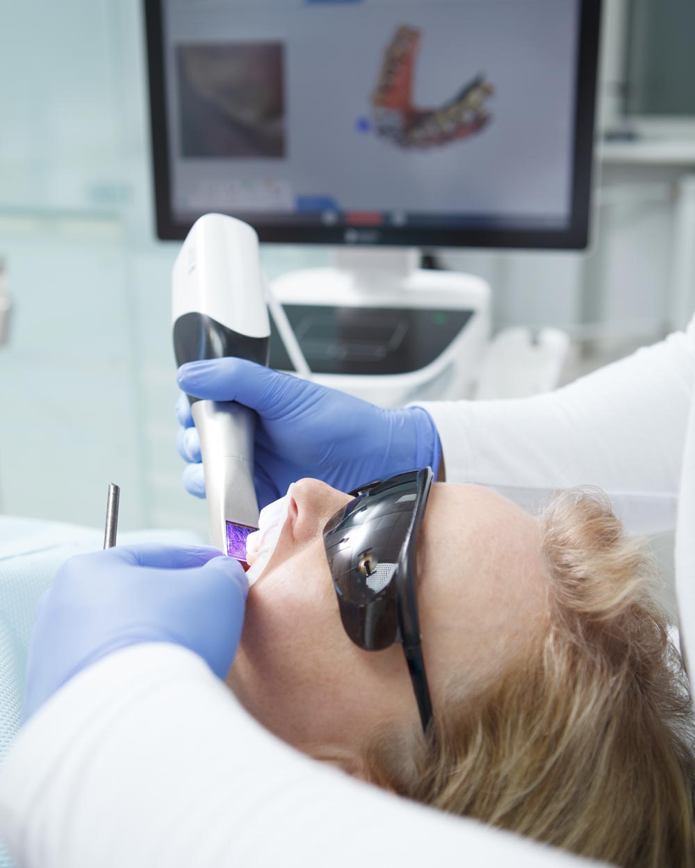 vertical close up of a female patient having dental scanning done by her dentist